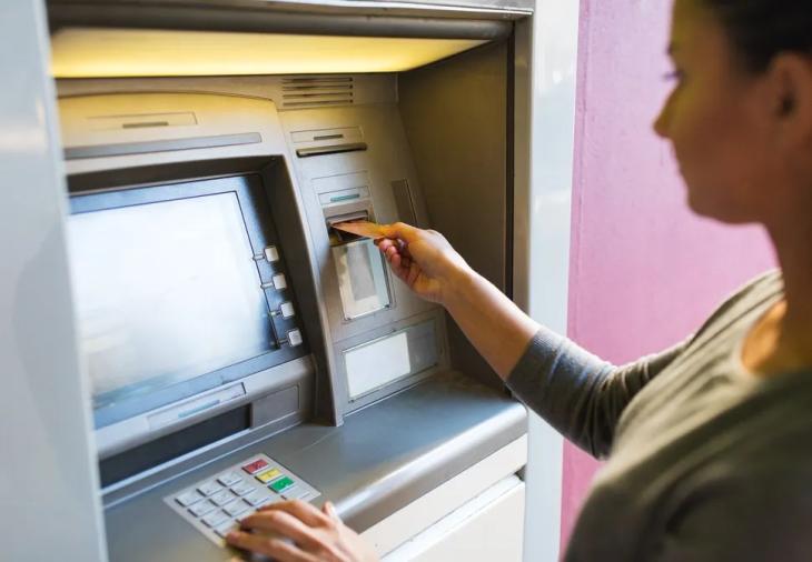 Persona operando en un cajero autom&aacute;tico para cobrar su salario.