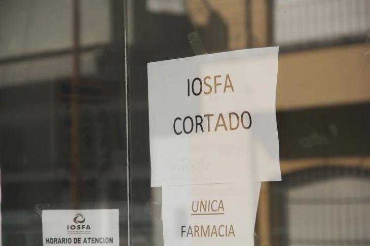 Cartel “IOSFA cortado” en la vidriera de una farmacia